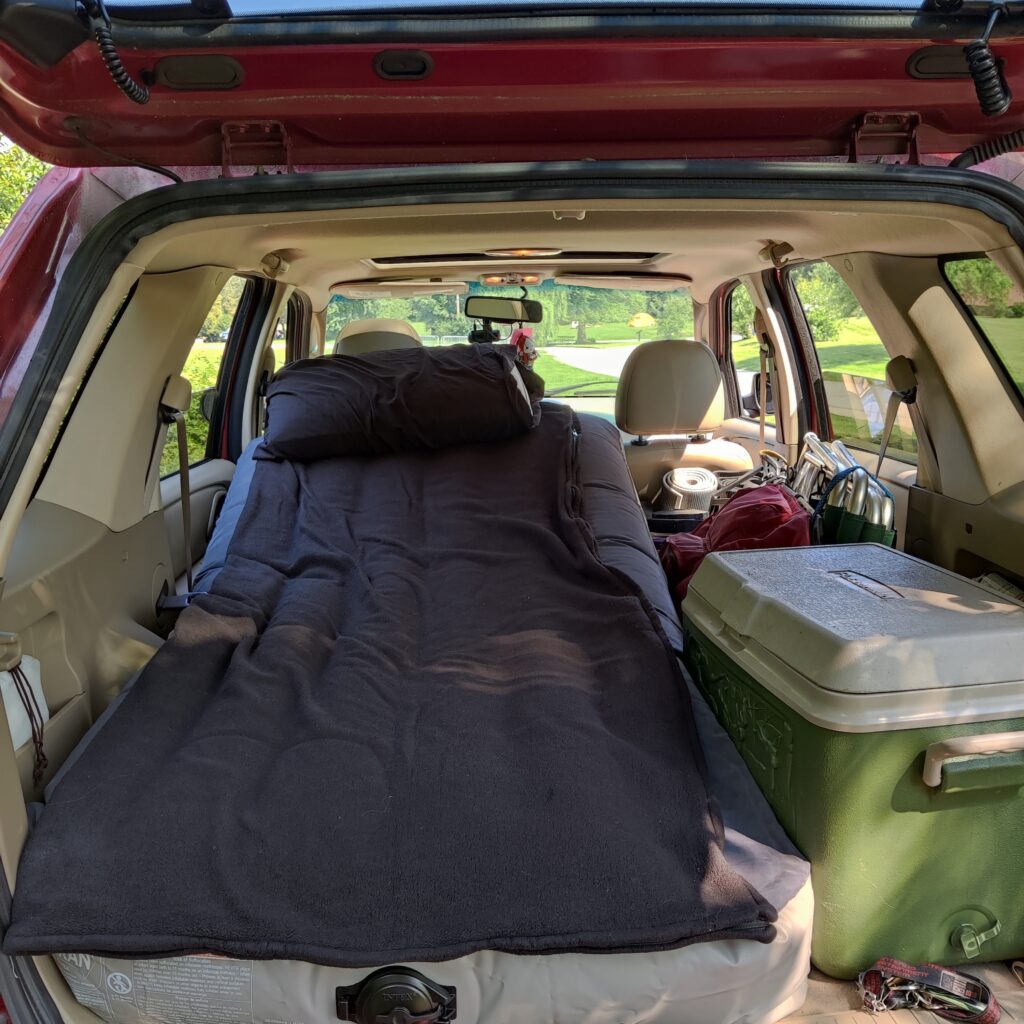 When I'm camping solo, I can fit my whole setup into my car. This image shows I have my air mattress on one side of the SUV, and my cooler and hiking bag on the other side.