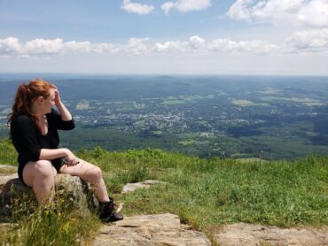 Halliday sitting at the top of Mt Greylock, practicing mindfulness while appreciating the view of the town below.